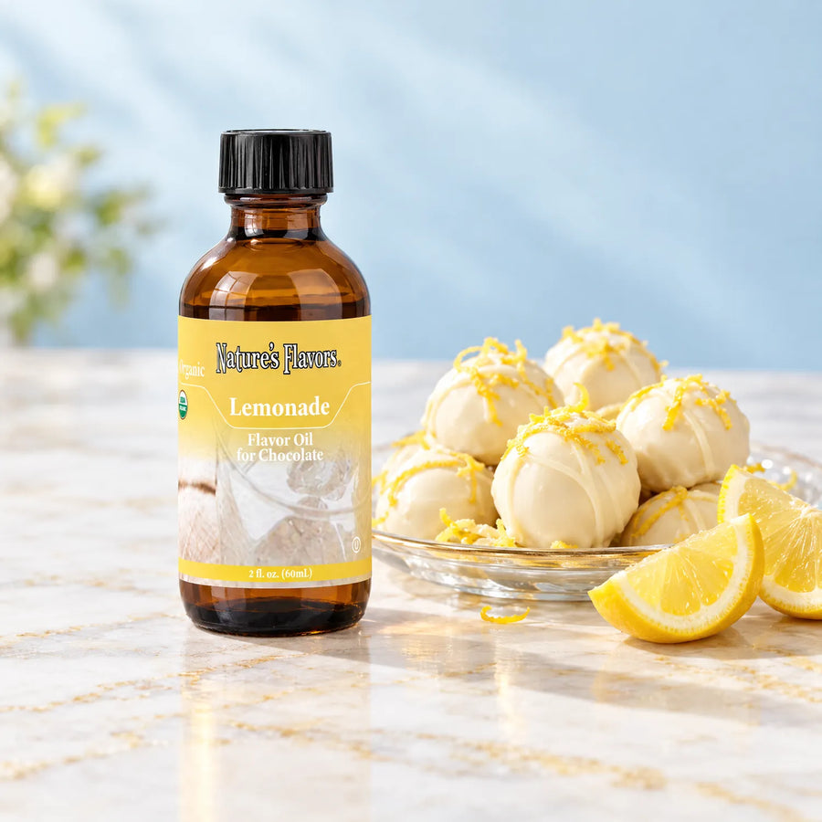 Nature's Flavors Organic Lemonade Flavor Oil For Chocolate, 2-ounce bottle, with lemon wedges and white chocolate truffles on marble.