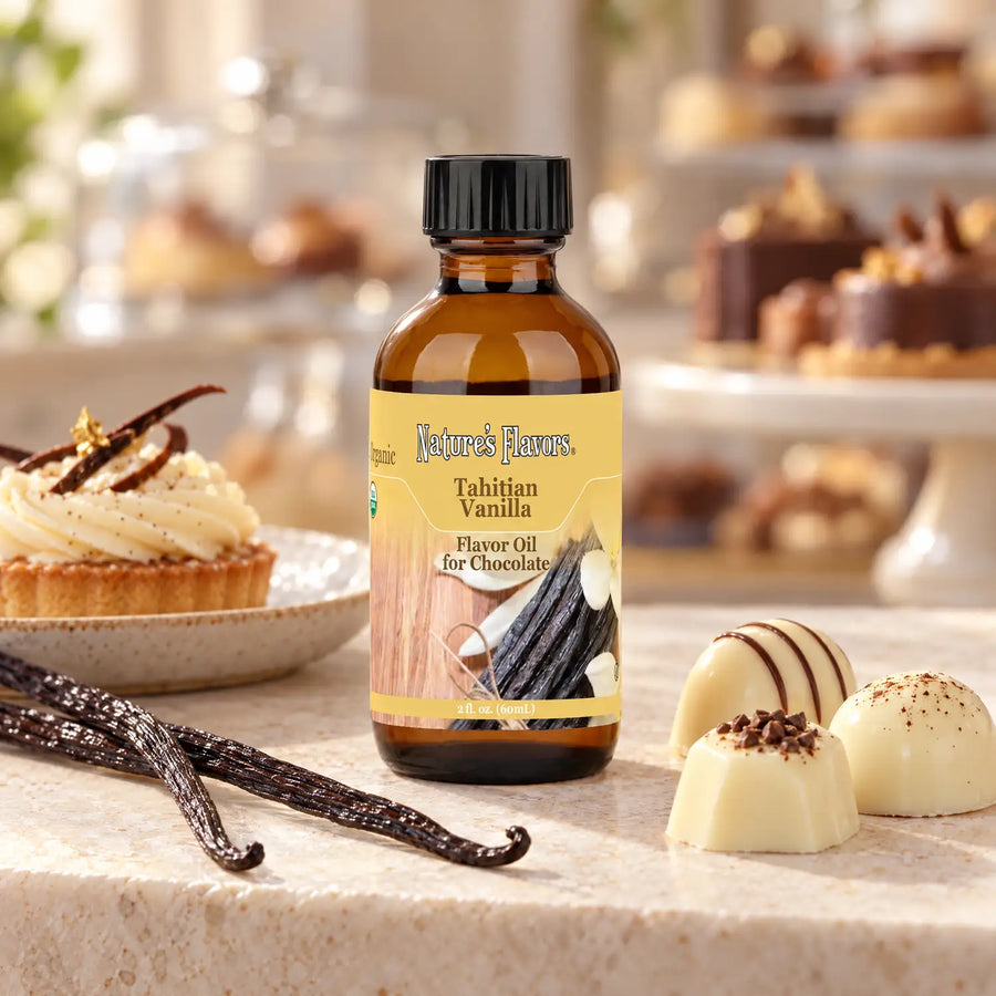 Nature's Flavors Organic Tahitian Vanilla Flavor Oil for Chocolate bottle beside vanilla beans, a cream tartlet, and white chocolate bonbons.