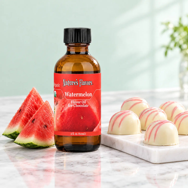 Nature's Flavors Organic Watermelon Flavor Oil For Chocolate, 2-ounce bottle, with watermelon slices and white chocolate bonbons on marble.