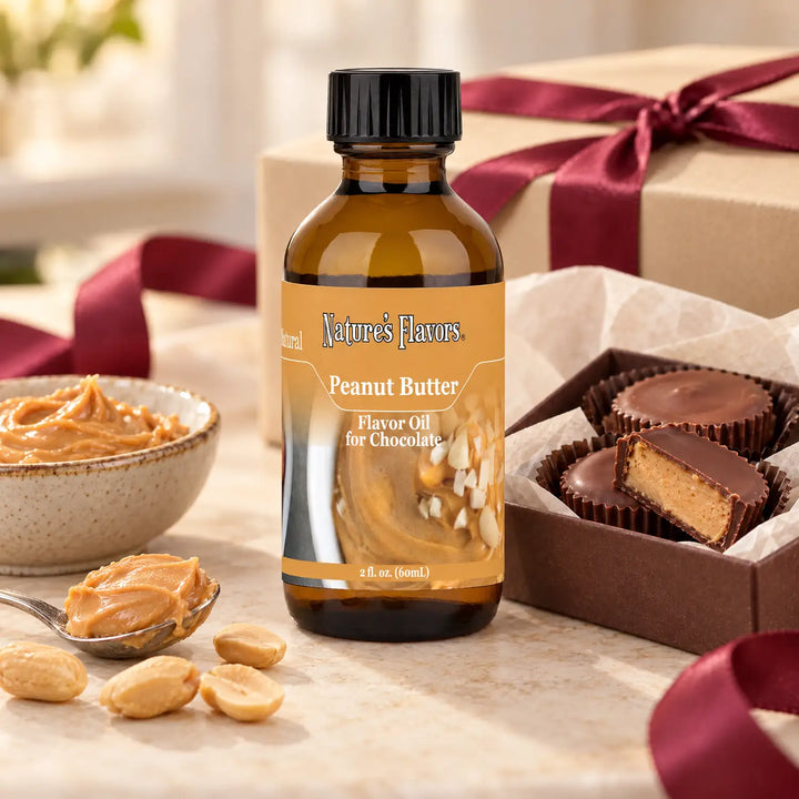 Nature's Flavors Peanut Butter Flavor Oil for Chocolate bottle beside peanut butter, peanuts, and chocolate cups in an open gift box.