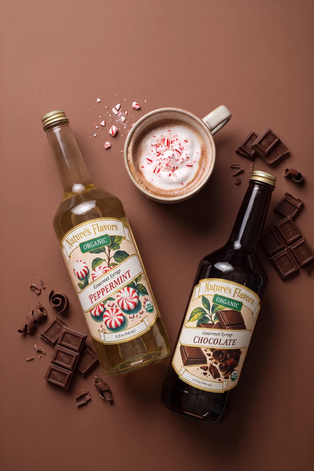 Nature's Flavors Organic Peppermint and Organic Chocolate gourmet syrup bottles beside a mocha topped with foam and crushed candy cane