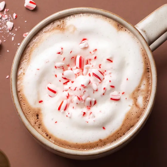A full mug of peppermint mocha topped with foam and crushed candy cane