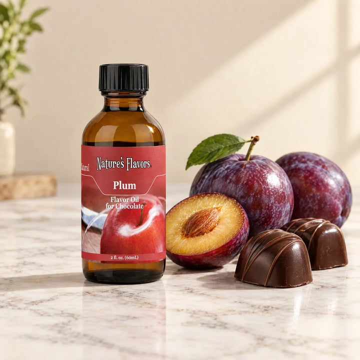 Nature's Flavors Plum Flavor Oil for Chocolate, 2-ounce bottle, with plums and dark chocolate bonbons on marble.