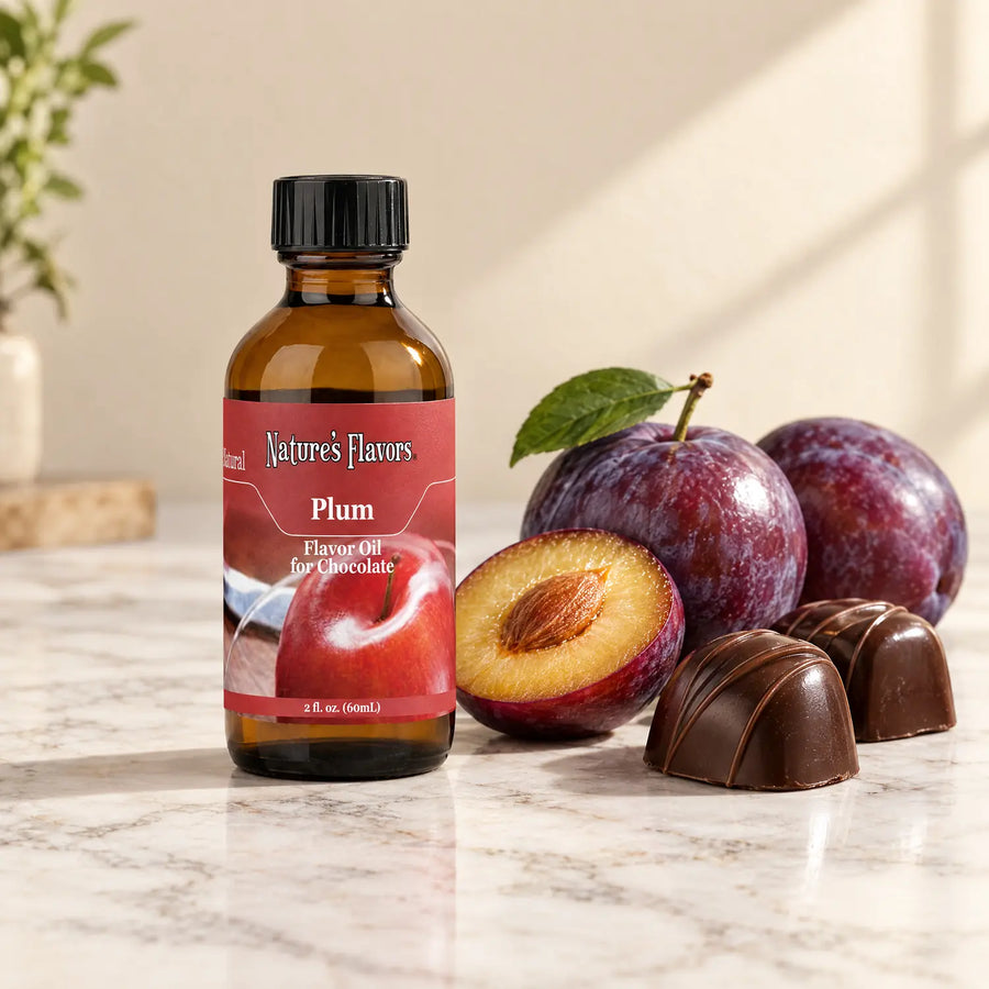 Nature's Flavors Plum Flavor Oil for Chocolate, 2-ounce bottle, with plums and dark chocolate bonbons on marble.
