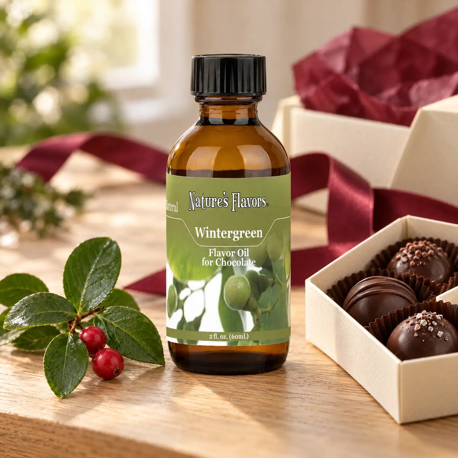 Nature's Flavors Wintergreen Flavor Oil for Chocolate bottle beside wintergreen leaves, red berries, and a box of chocolate truffles.