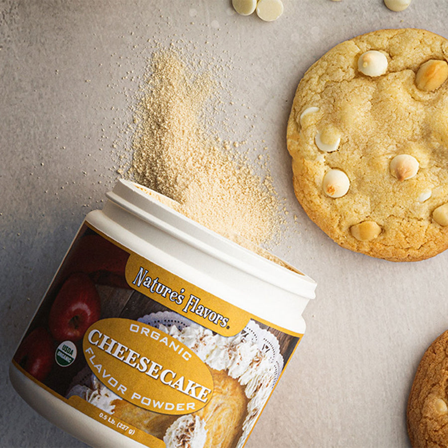 An open tub labeled, "Organic cheesecake flavor powder" lying next to cookies. 